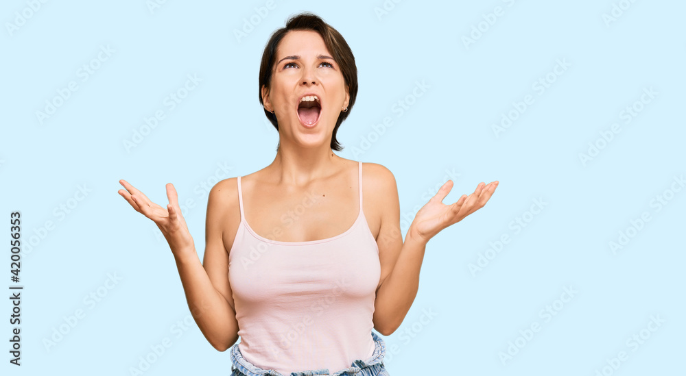 Young brunette woman with short hair wearing casual summer clothes crazy and mad shouting and yelling with aggressive expression and arms raised. frustration concept. Young brunette woman with short hair wearing casual summer clothes crazy and mad shouting and yelling with aggressive expression and arms raised. frustration concept.