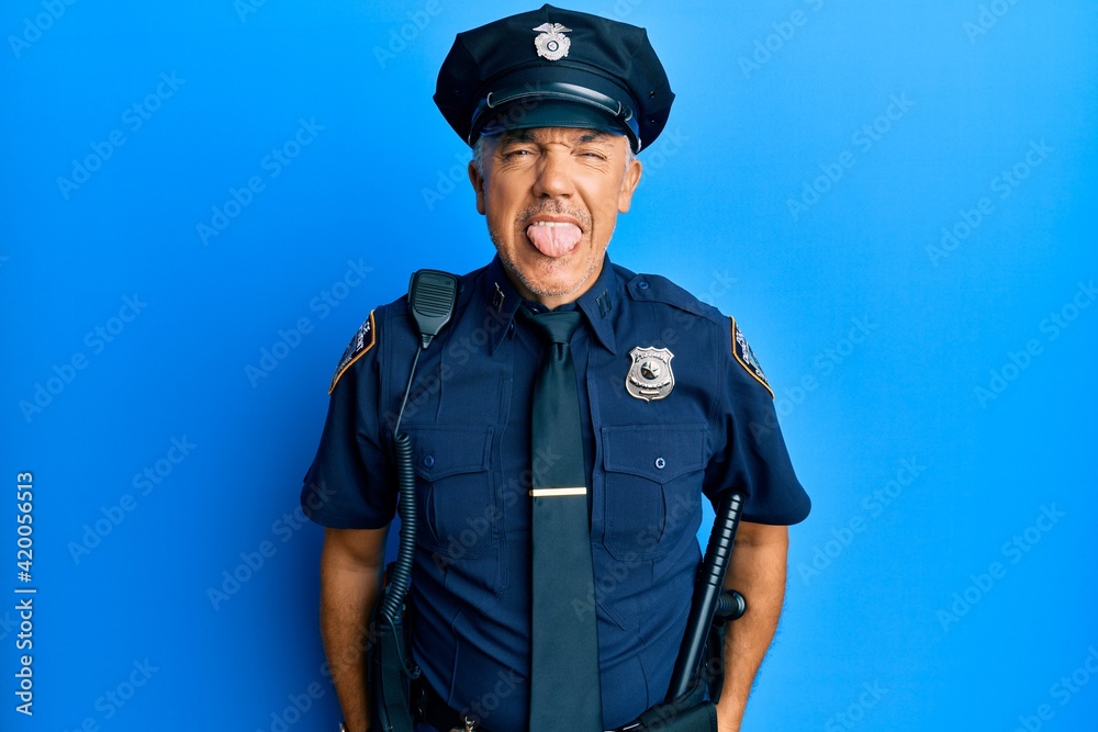 Handsome middle age mature man wearing police uniform sticking tongue out happy with funny expression. emotion concept. Handsome middle age mature man wearing police uniform sticking tongue out happy with funny expression. emotion concept.