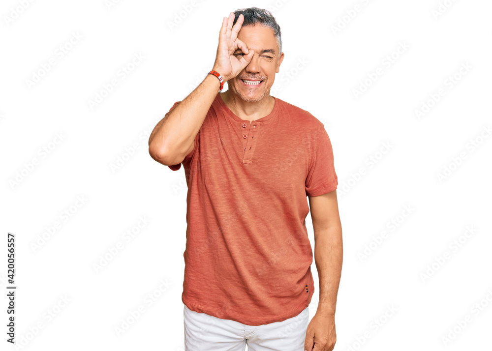Handsome middle age man wearing casual clothes doing ok gesture with hand smiling, eye looking through fingers with happy face.