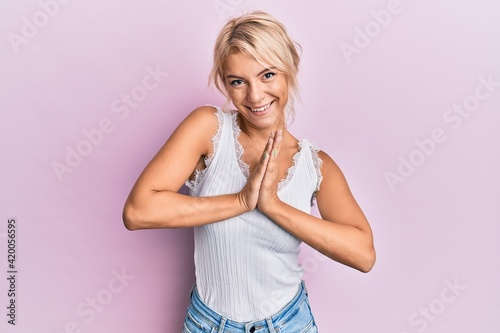 Young blonde girl wearing casual clothes praying with hands together asking for forgiveness smiling confident. © Krakenimages.com