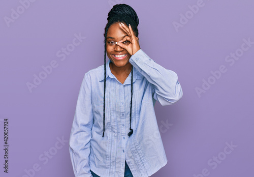 Young african american woman wearing casual clothes doing ok gesture with hand smiling, eye looking through fingers with happy face.