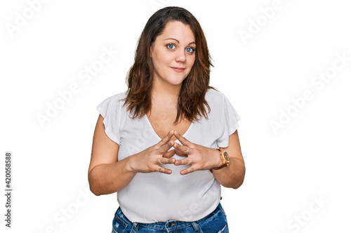 Young plus size woman wearing casual white t shirt hands together and fingers crossed smiling relaxed and cheerful. success and optimistic