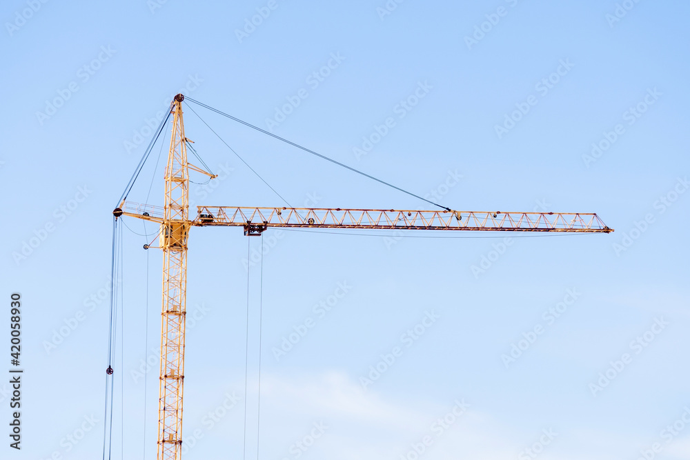 yellow construction crane on a blue sky background. space for copying text