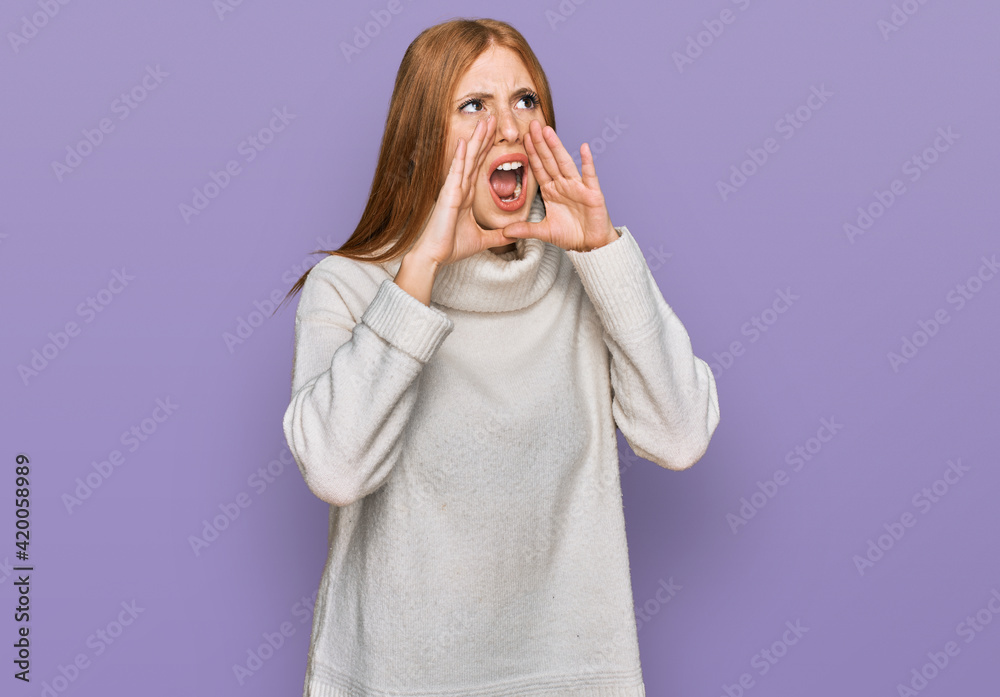 Young irish woman wearing casual winter sweater shouting angry out loud with hands over mouth Young irish woman wearing casual winter sweater shouting angry out loud with hands over mouth