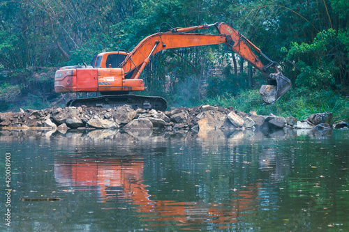 Macco truck shovels scooping rocks to fill the river