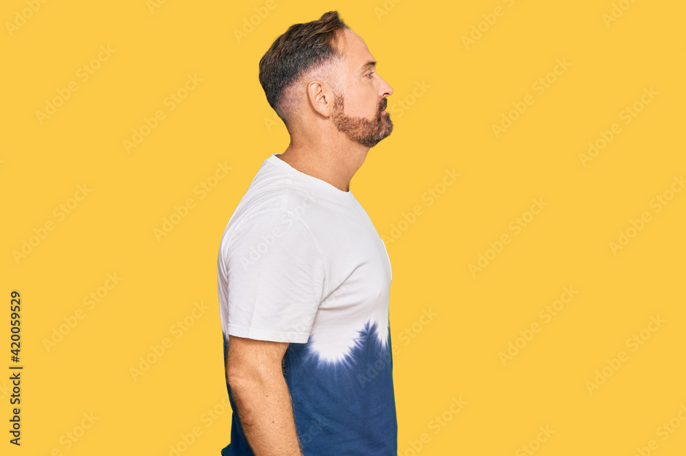 Handsome middle age man wearing casual tie dye tshirt looking to side, relax profile pose with natural face with confident smile. Handsome middle age man wearing casual tie dye tshirt looking to side, relax profile pose with natural face with confident smile.