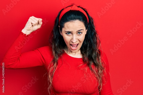 Young hispanic woman wearing casual clothes angry and mad raising fist frustrated and furious while shouting with anger. rage and aggressive concept.