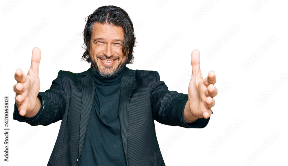 Middle age handsome man wearing business clothes looking at the camera smiling with open arms for hug. cheerful expression embracing happiness. Middle age handsome man wearing business clothes looking at the camera smiling with open arms for hug. cheerful expression embracing happiness.