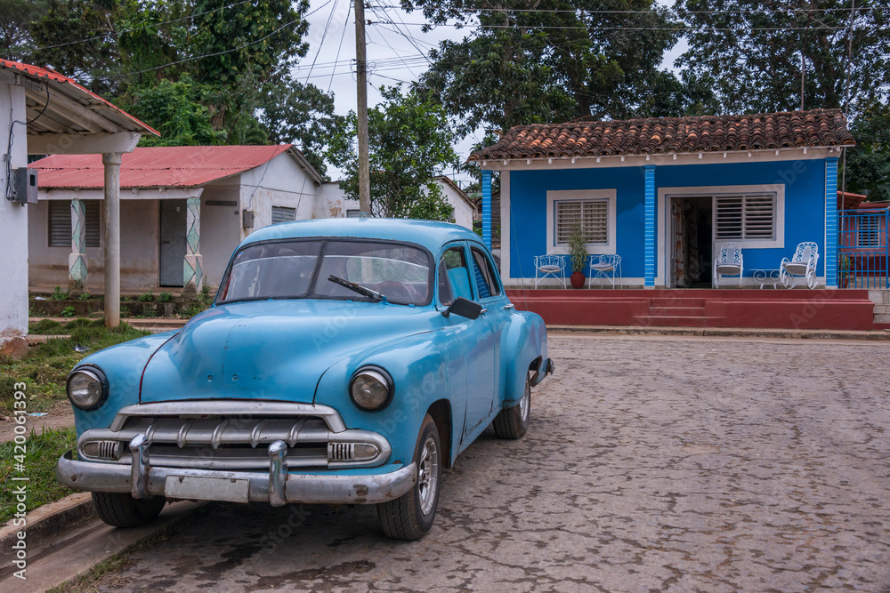 Viejo coche americano junto a unas casas en el pueblo de Viñales, Cuba
