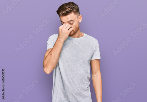 Young redhead man wearing casual grey t shirt tired rubbing nose and eyes feeling fatigue and headache. stress and frustration concept.