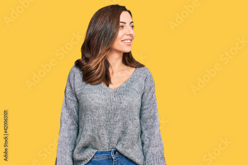 Young brunette woman wearing casual winter sweater looking away to side with smile on face, natural expression. laughing confident. © Krakenimages.com