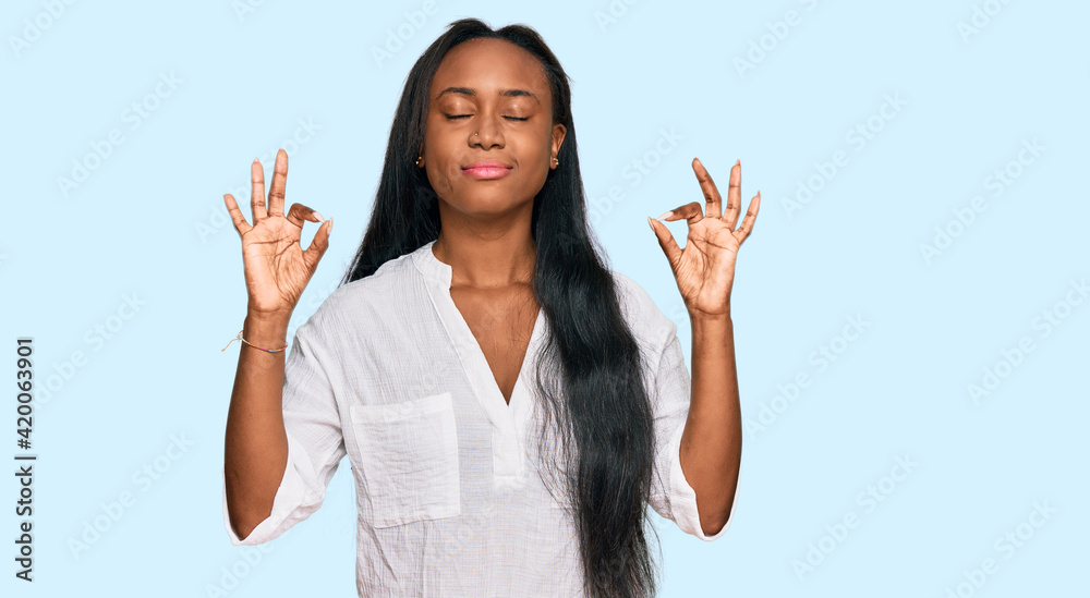 Young black woman wearing casual clothes relax and smiling with eyes closed doing meditation gesture with fingers. yoga concept. Young black woman wearing casual clothes relax and smiling with eyes closed doing meditation gesture with fingers. yoga concept.