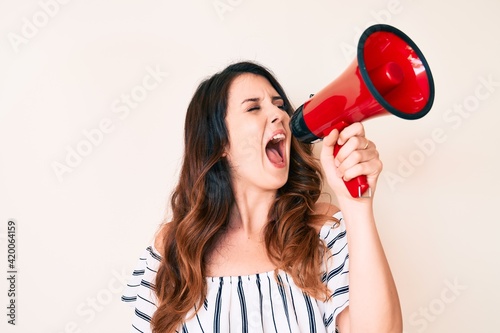 Young woman shouting exited throung megaphone, yelling and screaming protesting photo