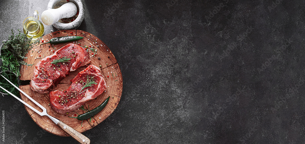fresh raw striploin steak on a wooden board on a wooden background with salt and pepper in a rustic style.