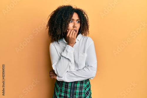 Beautiful african american woman with afro hair wearing scholar skirt looking stressed and nervous with hands on mouth biting nails. anxiety problem. © Krakenimages.com