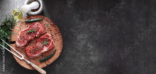 Obraz na płótnie fresh raw striploin steak on a wooden board on a wooden background with salt and pepper in a rustic style. w salonie