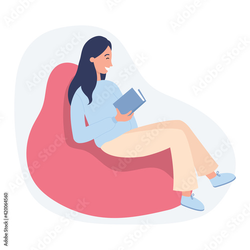 Girl sitting with book at home in a beanbag chair. Hobby, leisure and education concept
