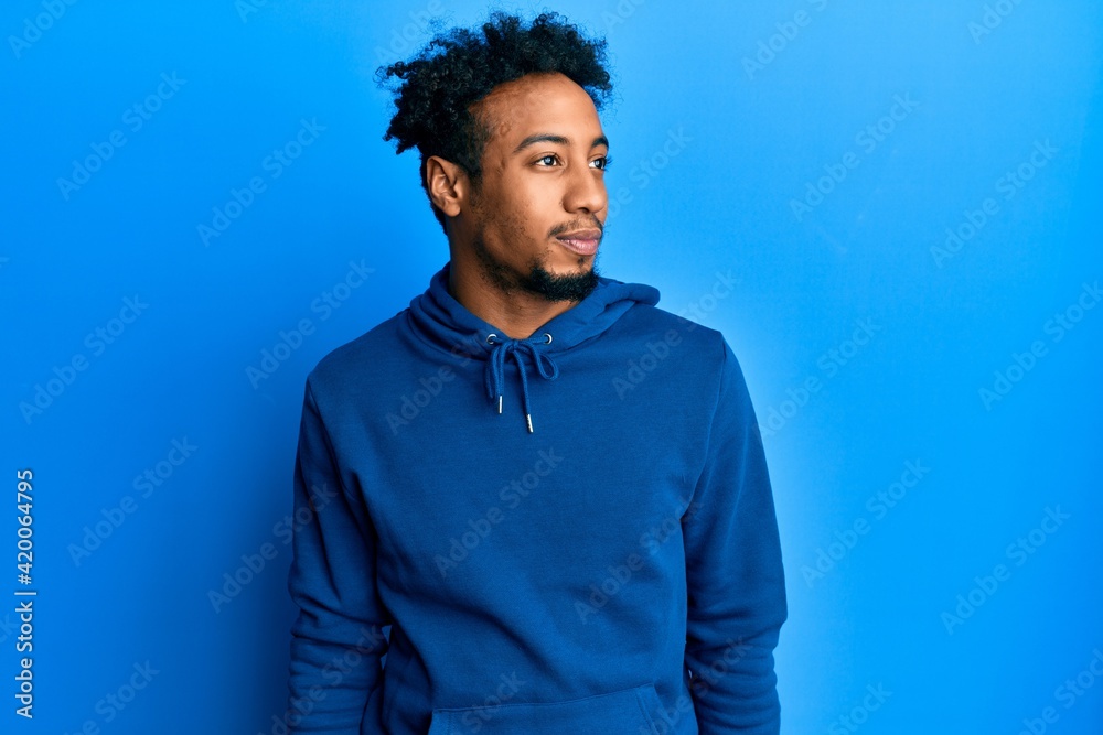 Young african american man with beard wearing casual sweatshirt looking to side, relax profile pose with natural face and confident smile. Young african american man with beard wearing casual sweatshirt looking to side, relax profile pose with natural face and confident smile.