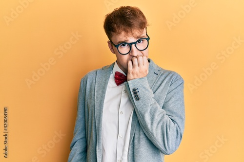 Young caucasian nerd man wearing glasses wearing hipster elegant look with bowtie looking stressed and nervous with hands on mouth biting nails. anxiety problem.