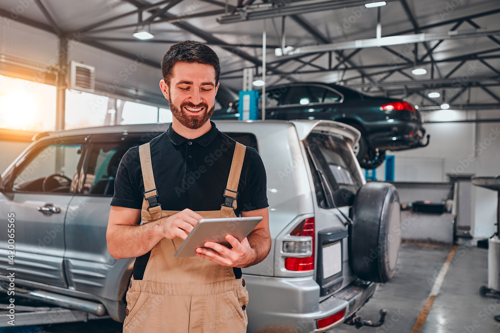 Portrait of young mechanic holding digital tablet in his auto repair shop. Portrait of young mechanic holding digital tablet in his auto repair shop.