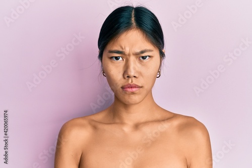 Fotografie Young chinese woman standing topless showing skin skeptic and nervous, frowning upset because of problem