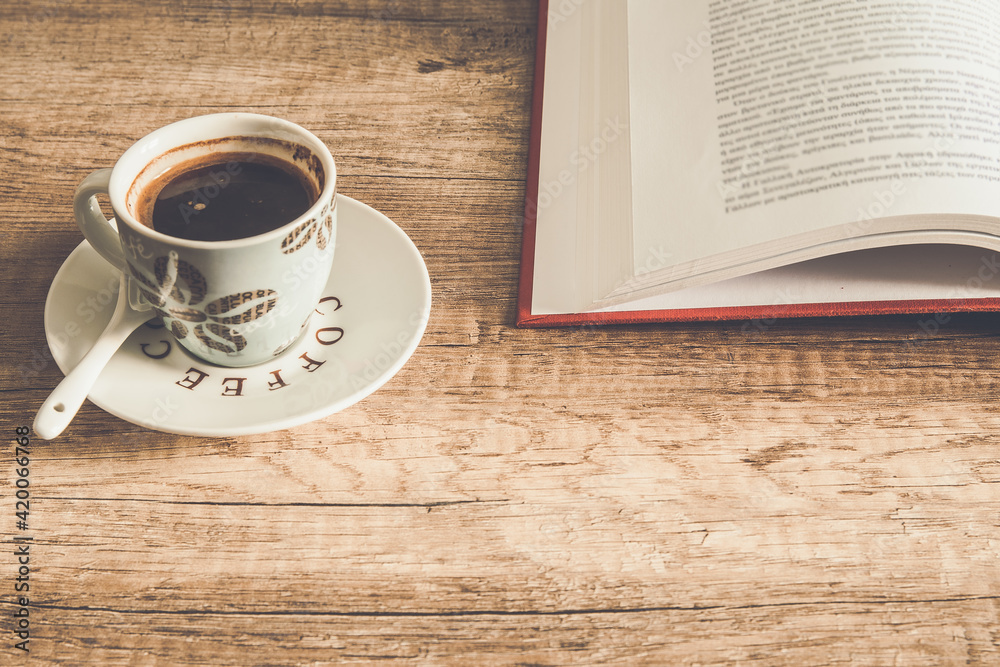 A cup of coffee and an open book on a wooden rustic table A cup of coffee and an open book on a wooden rustic table
