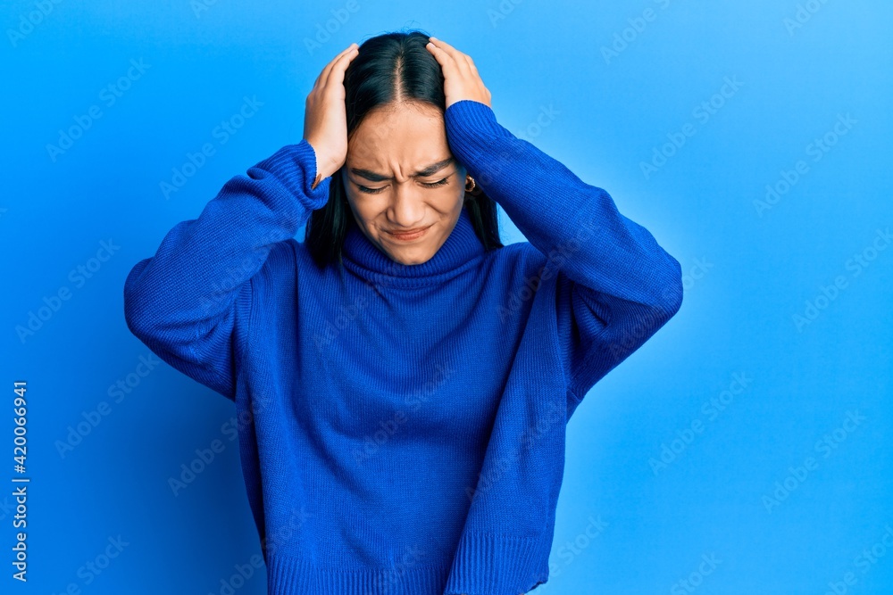 Young asian woman wearing casual winter sweater suffering from headache desperate and stressed because pain and migraine. hands on head. Young asian woman wearing casual winter sweater suffering from headache desperate and stressed because pain and migraine. hands on head.