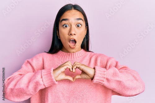 Young asian woman doing heart symbol with hands afraid and shocked with surprise and amazed expression, fear and excited face.