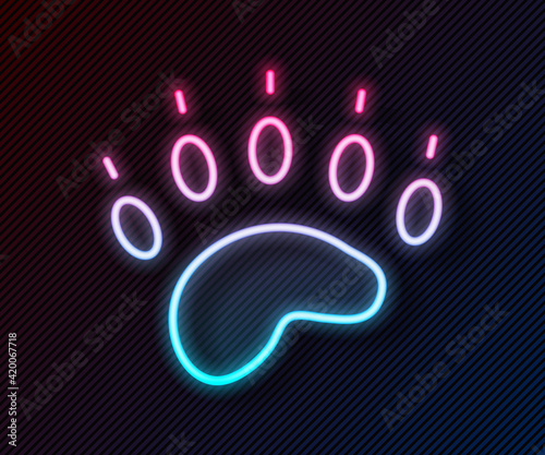 Glowing neon line Bear paw footprint icon isolated on black background. Vector