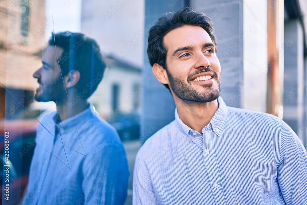 Young hispanic man smiling happy leaning on the wall at the city. Young hispanic man smiling happy leaning on the wall at the city.