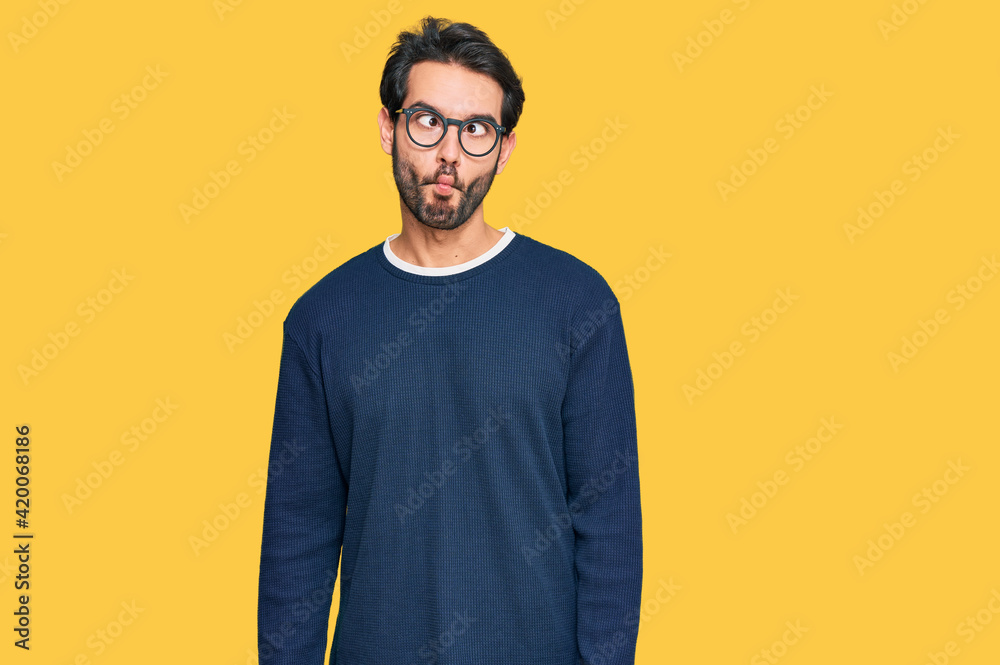 Young hispanic man wearing casual clothes and glasses making fish face with lips, crazy and comical gesture. funny expression. Young hispanic man wearing casual clothes and glasses making fish face with lips, crazy and comical gesture. funny expression.