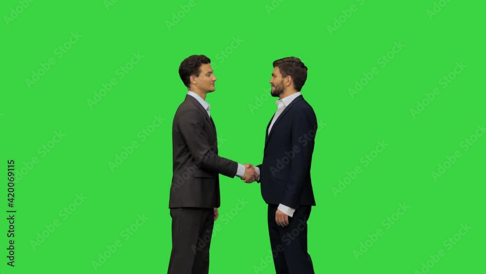 Two young men in suits greet each other on a Green Screen, Chroma Key. Two young men in suits greet each other on a Green Screen, Chroma Key.
