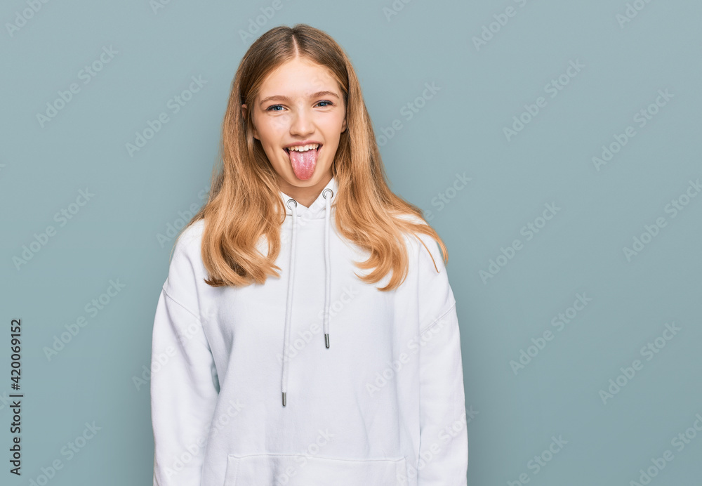 Beautiful young caucasian girl wearing casual sweatshirt sticking tongue out happy with funny expression. emotion concept. Beautiful young caucasian girl wearing casual sweatshirt sticking tongue out happy with funny expression. emotion concept.