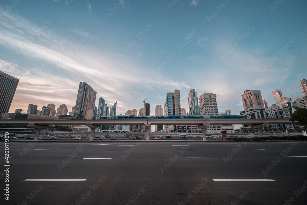Moving Dubai metro train on the bridge against upscale community skyline. Panoramic view for a modern city and infrastructure. Dubai Metro against skyline at Sheikh Zayed road.
