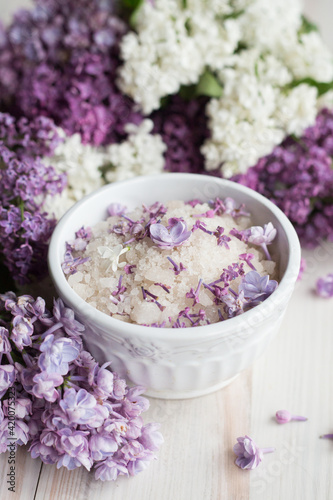 Homemade bath salt with fresh spring lilac flowers  home healthy spa  relaxation  light wooden background  vertical