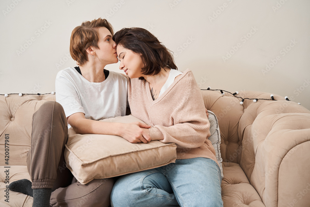 Couple in love enjoying their free time, while sitting on a couch Couple in love enjoying their free time, while sitting on a couch