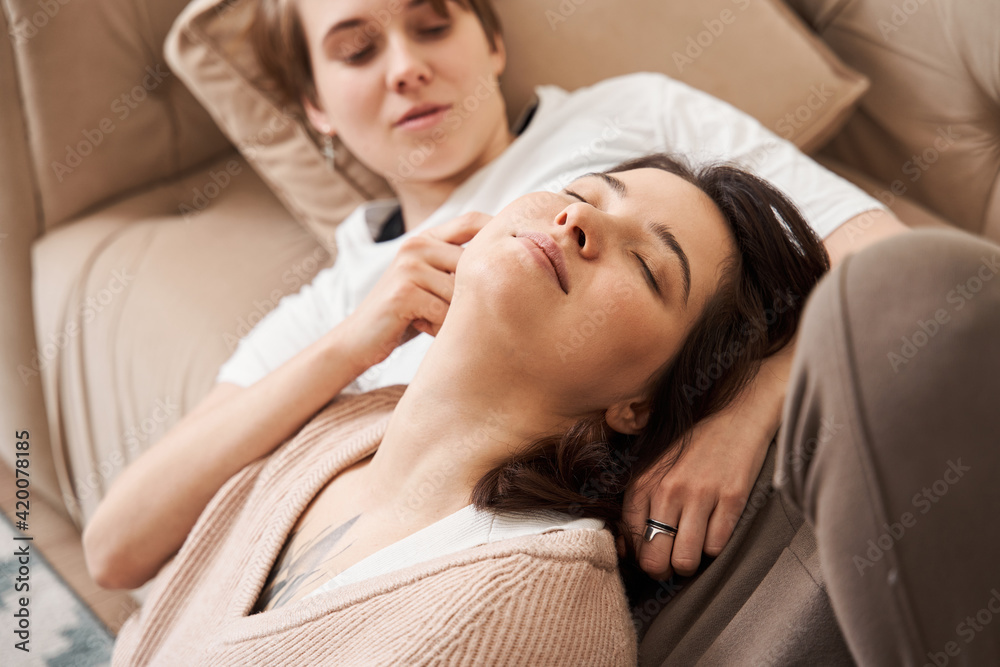 Romantic lesbian couple in love embracing and cuddling at the sofa Romantic lesbian couple in love embracing and cuddling at the sofa