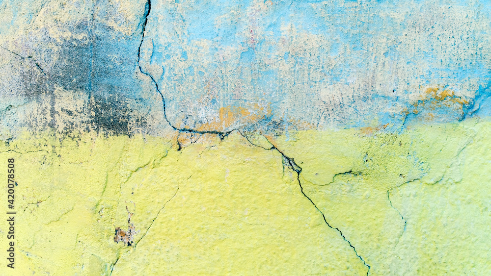 Obraz premium A weathered old wall painted in pastel shades of yellow and blue.