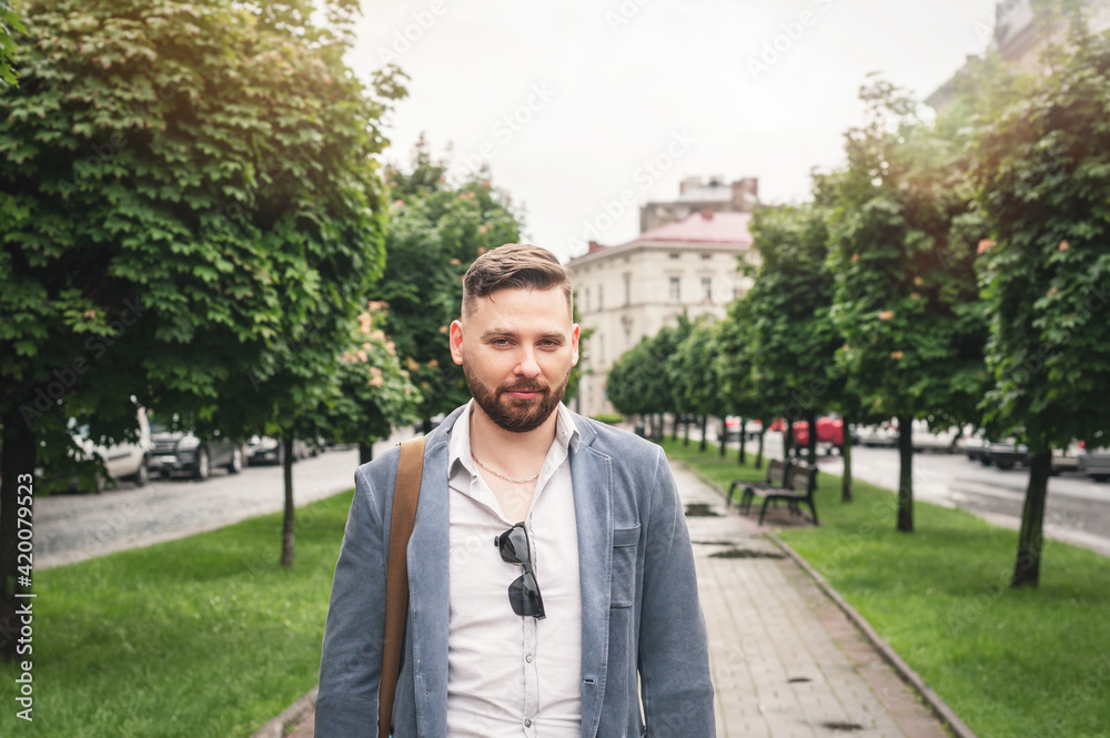 Handsome bearded businessman in classic suit and sun glasses and with bag is walking in city. Handsome bearded businessman in classic suit and sun glasses and with bag is walking in city.