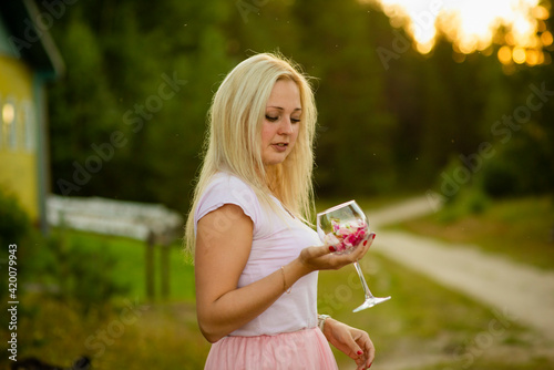 blonde girl with a glass of flowers in summer, selective focus
