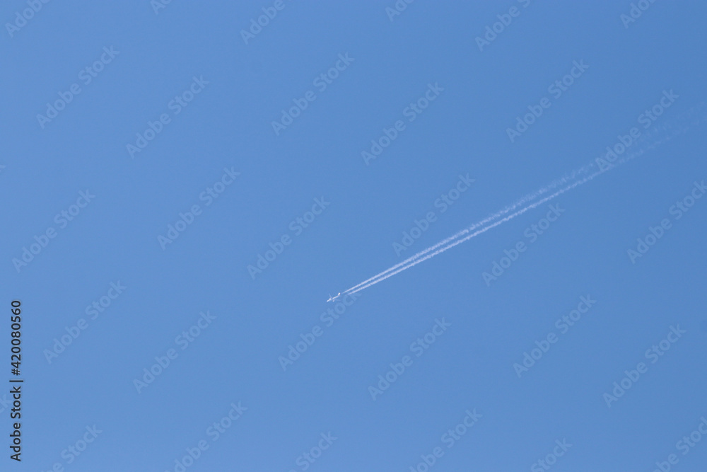 The airplane fast movement with condensation lines on the blue sky The airplane fast movement with condensation lines on the blue sky