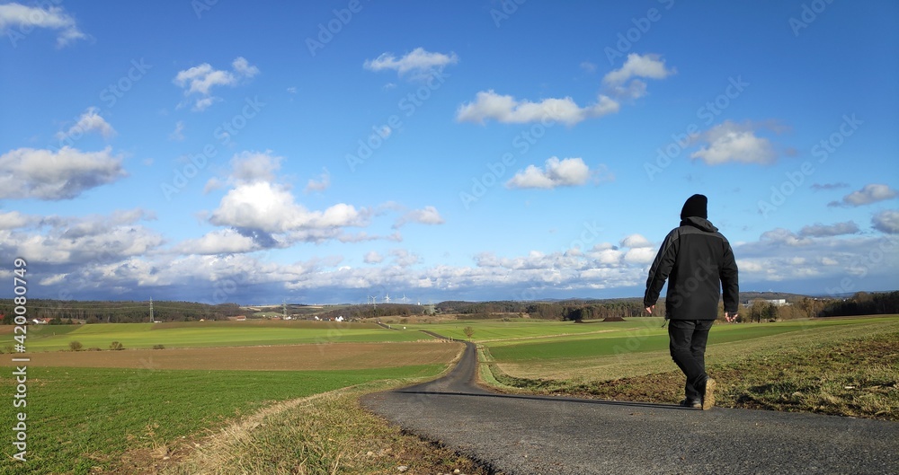 A man walking down a country backroad in rural Bavaria near Grub am Forst