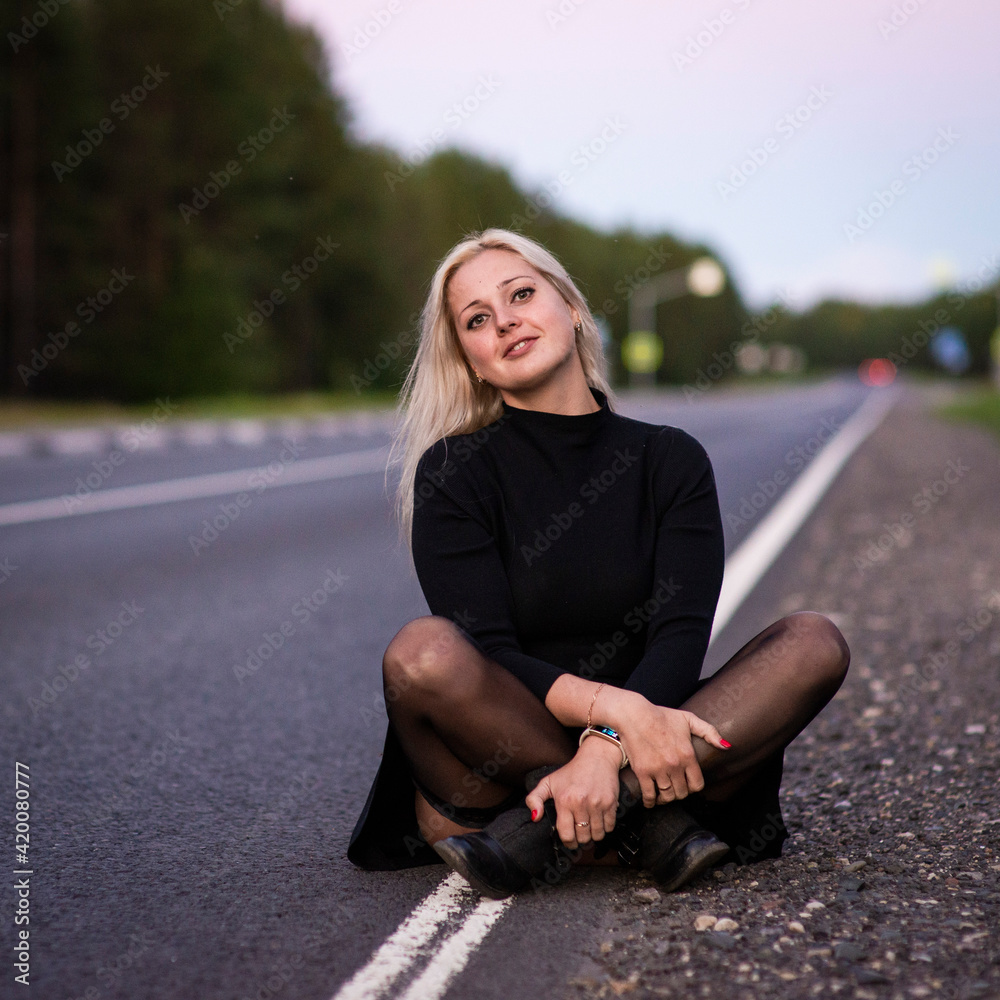 Fototapeta premium blonde girl in black dress on the road, selective focus