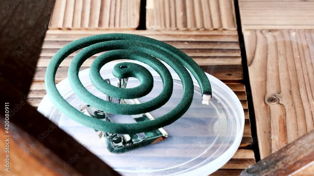 Burning mosquito repellent coil with smoke at home outdoor patio to ward off mosquitoes Burning mosquito repellent coil with smoke at home outdoor patio to ward off mosquitoes