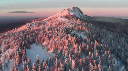 beautiful sunset above snow mountains, aerial view. national park Taganay in Russia. scenic winter landscape, nature background. majestic red sunset light on treetops and cliffs. photo