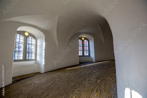 Spiraling ramp inside the Round Tower of Copenhagen  Denmark. Two framed windows and light on top of them.