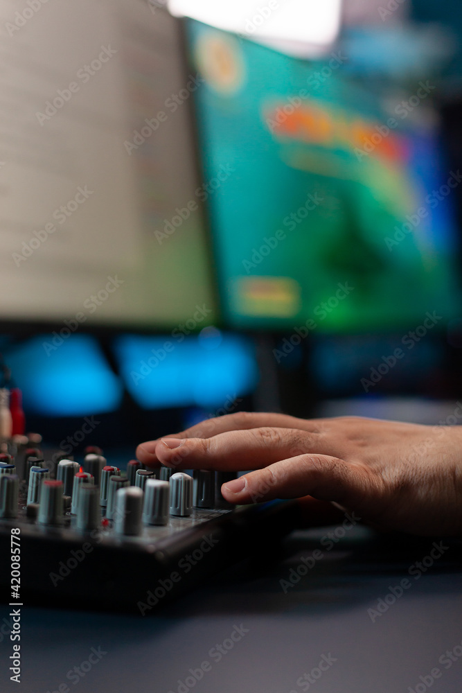 Fototapeta premium Close up of streamer checking mixer buttons for online gamimg championship playing shoother videogames in home studio