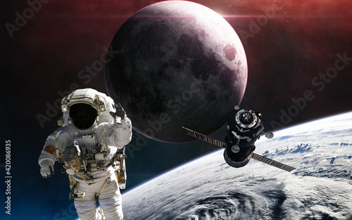 Astronaut and space station orbiting Earth. Moon. Solar system. Science fiction. Elements of this image furnished by NASA