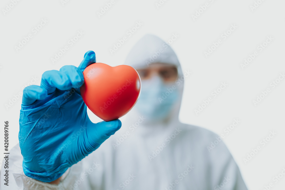 The doctor hold red heart and wearing personal protective equipment or ppe, mask, goggle and suit to protect COVID-19 infection. coronavirus, medical, healthcare concept The doctor hold red heart and wearing personal protective equipment or ppe, mask, goggle and suit to protect COVID-19 infection. coronavirus, medical, healthcare concept