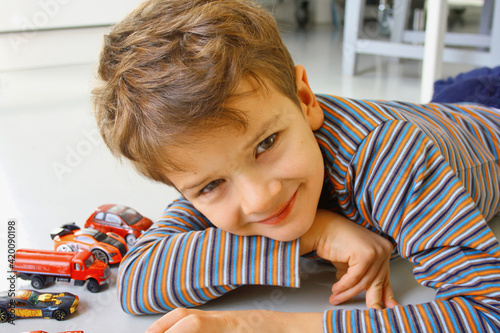 BAMBINO GIOCANDO CON AUTOMOBILI GIOCATTOLO SUL PAVIMENTO photo